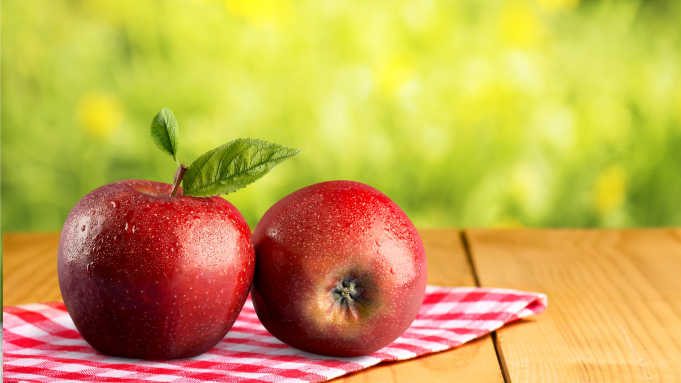 Два красных яблока в каплях воды лежат на полотенце 