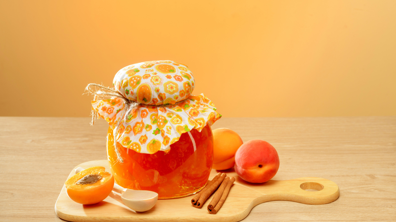 Банка абрикосового джема на столе с фруктами