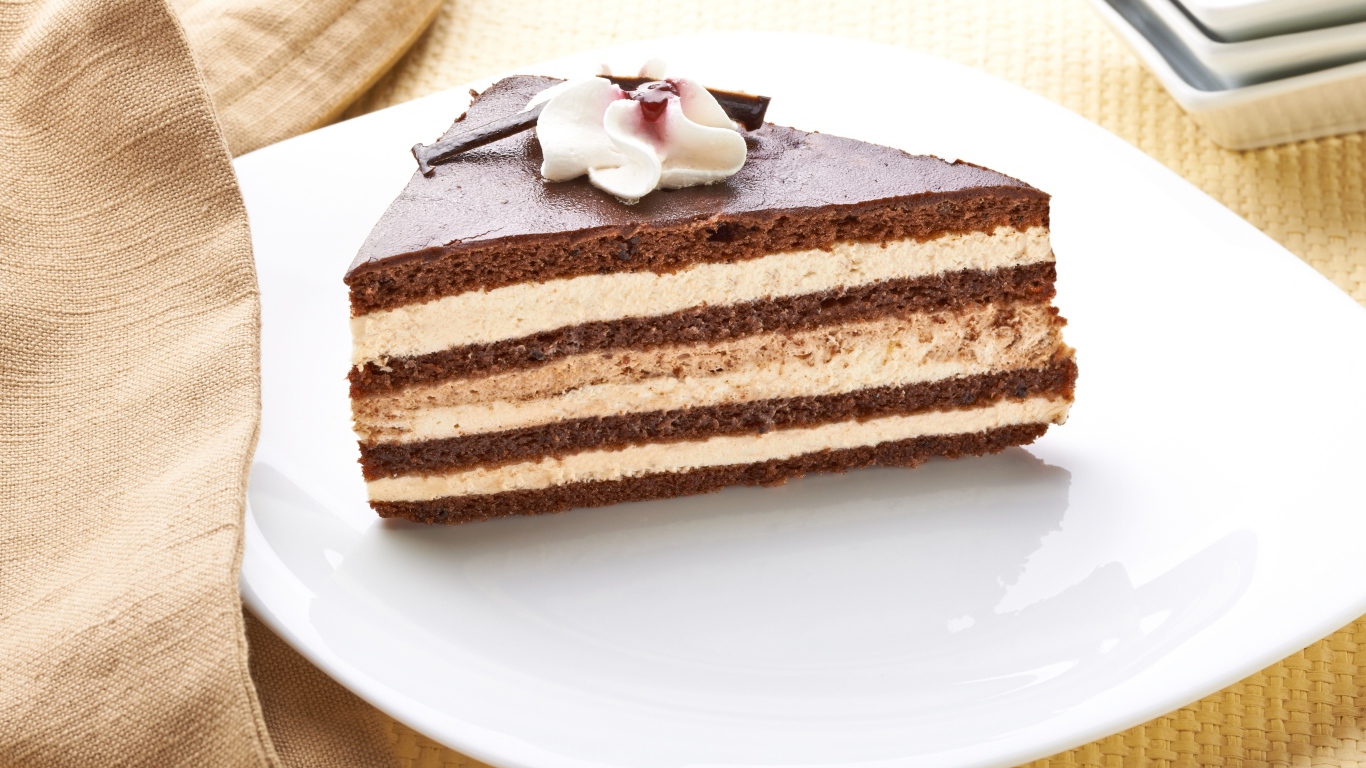 Большой кусок торта с кремом украшен цветком