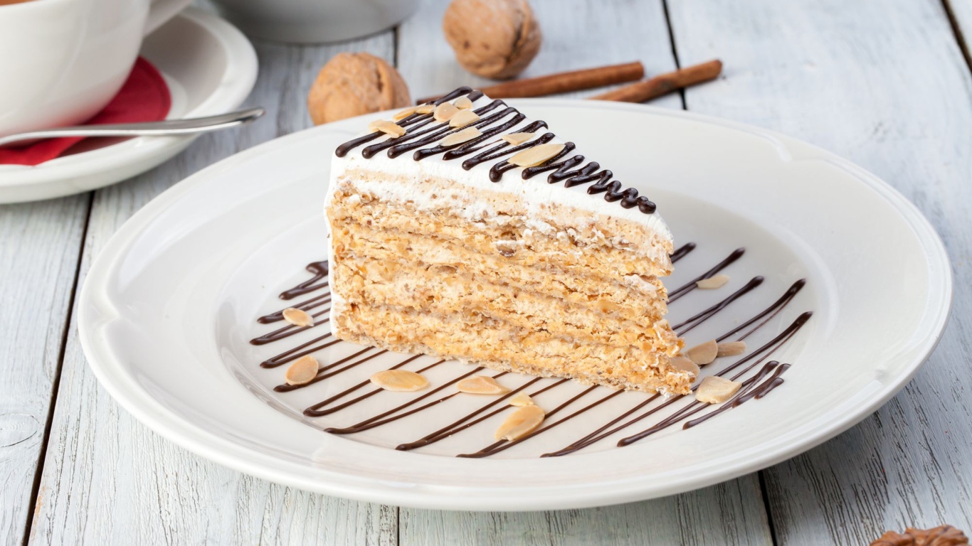 Кусок торта с орехами и шоколадом на белой тарелке