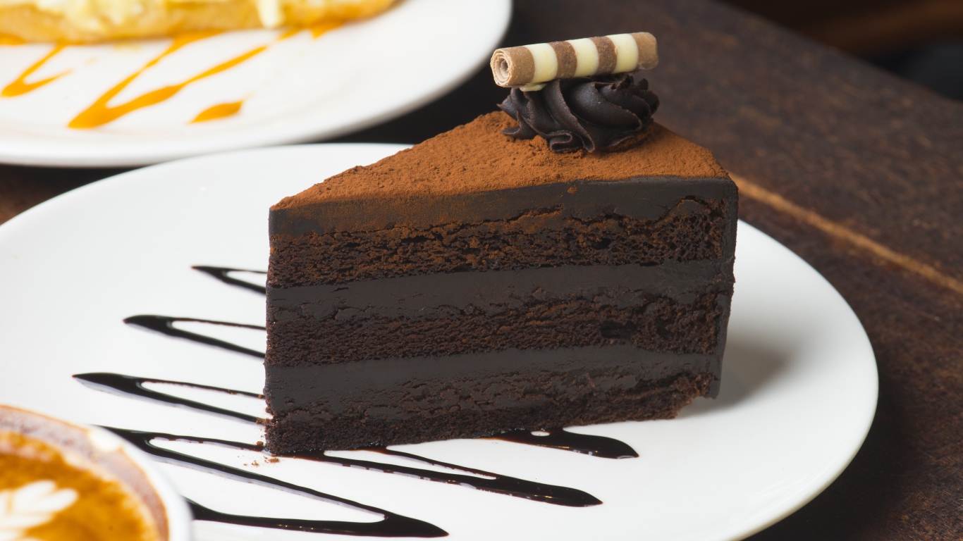 Кусок аппетитного шоколадного торта на белой тарелке