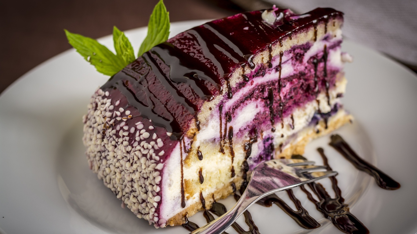 Кусок черничного пирога с джемом на белой тарелке с вилкой