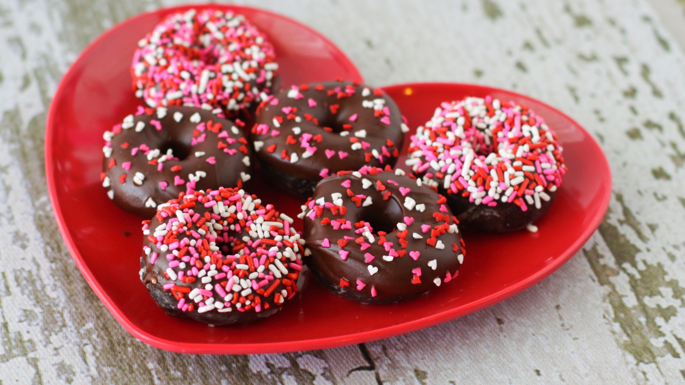 Аппетитные пончики на красной тарелке в форме сердца