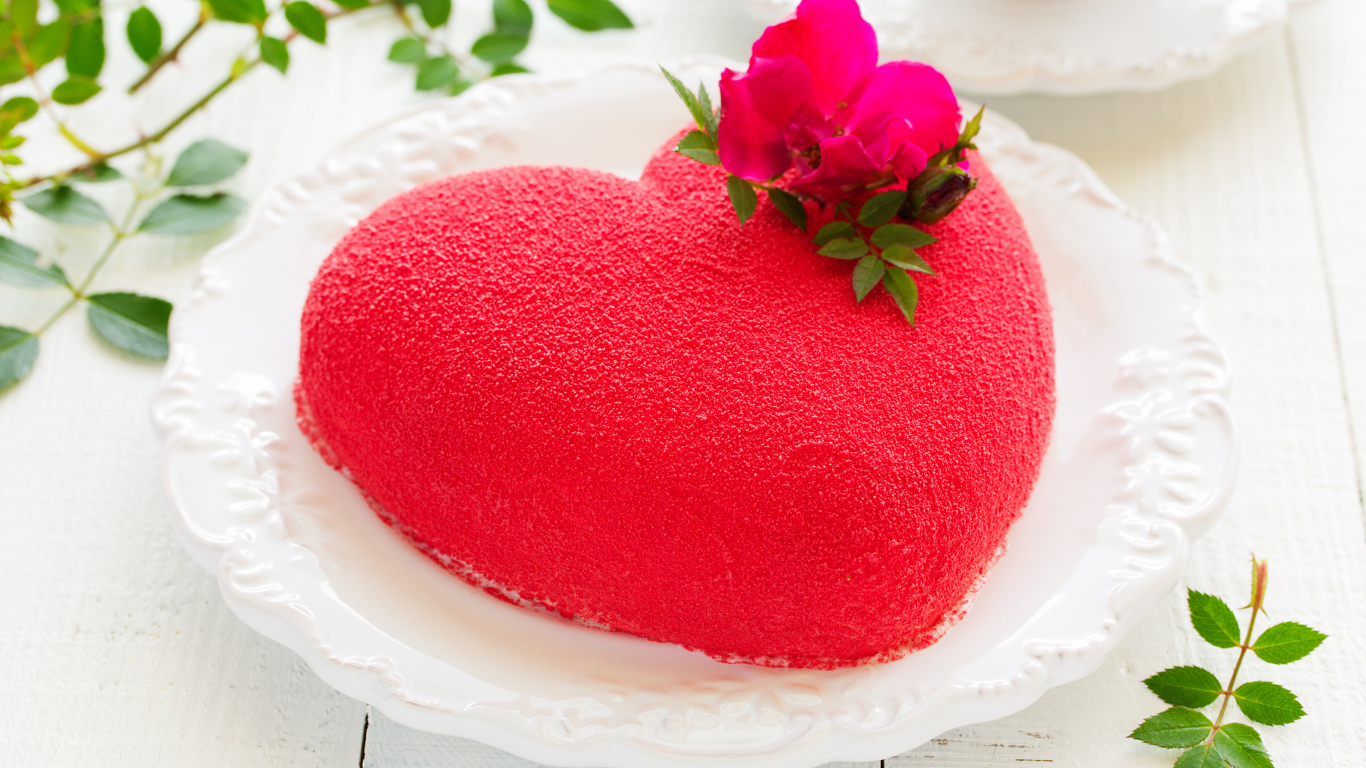 Красивый торт в форме сердца на белом блюде с красным цветком