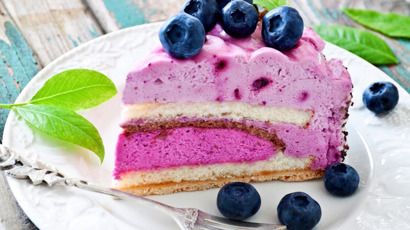 Торт с черничным муссом и свежими ягодами черники на белой тарелке 