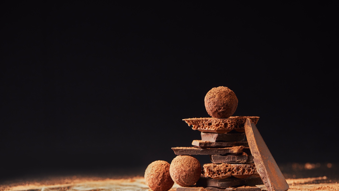 Шоколадные шарики и кусочки шоколада на черном фоне