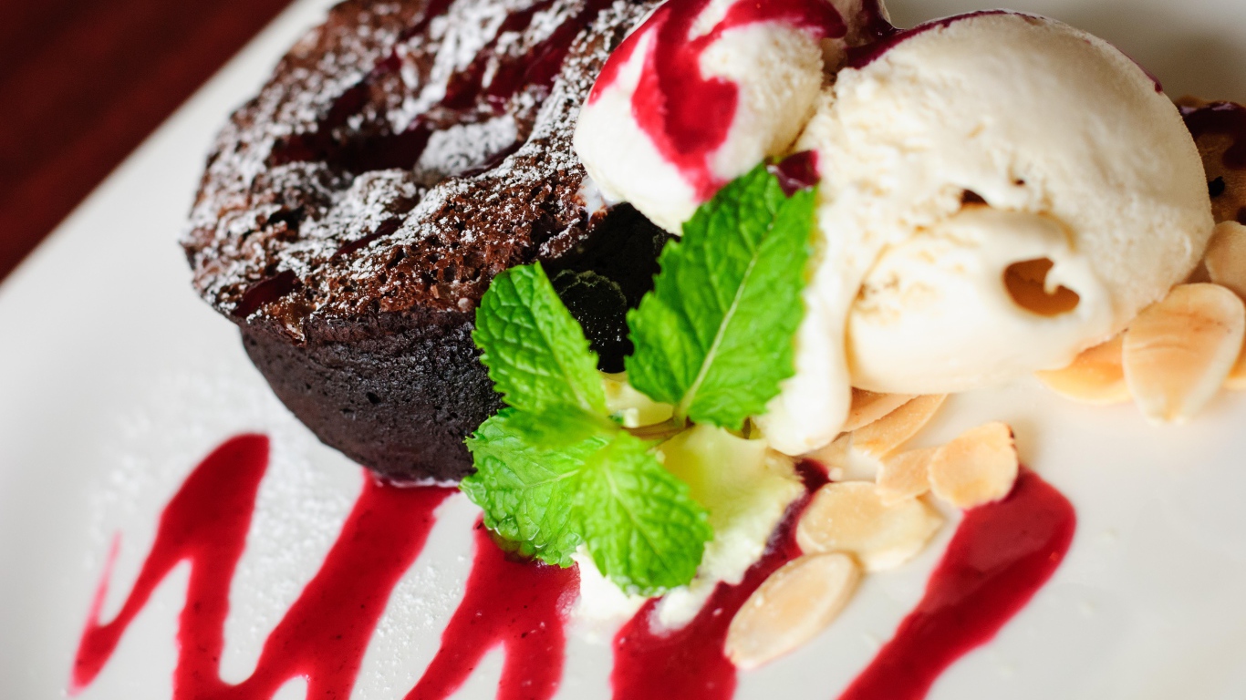 Шоколадное пирожное с мороженым и джемом на тарелке