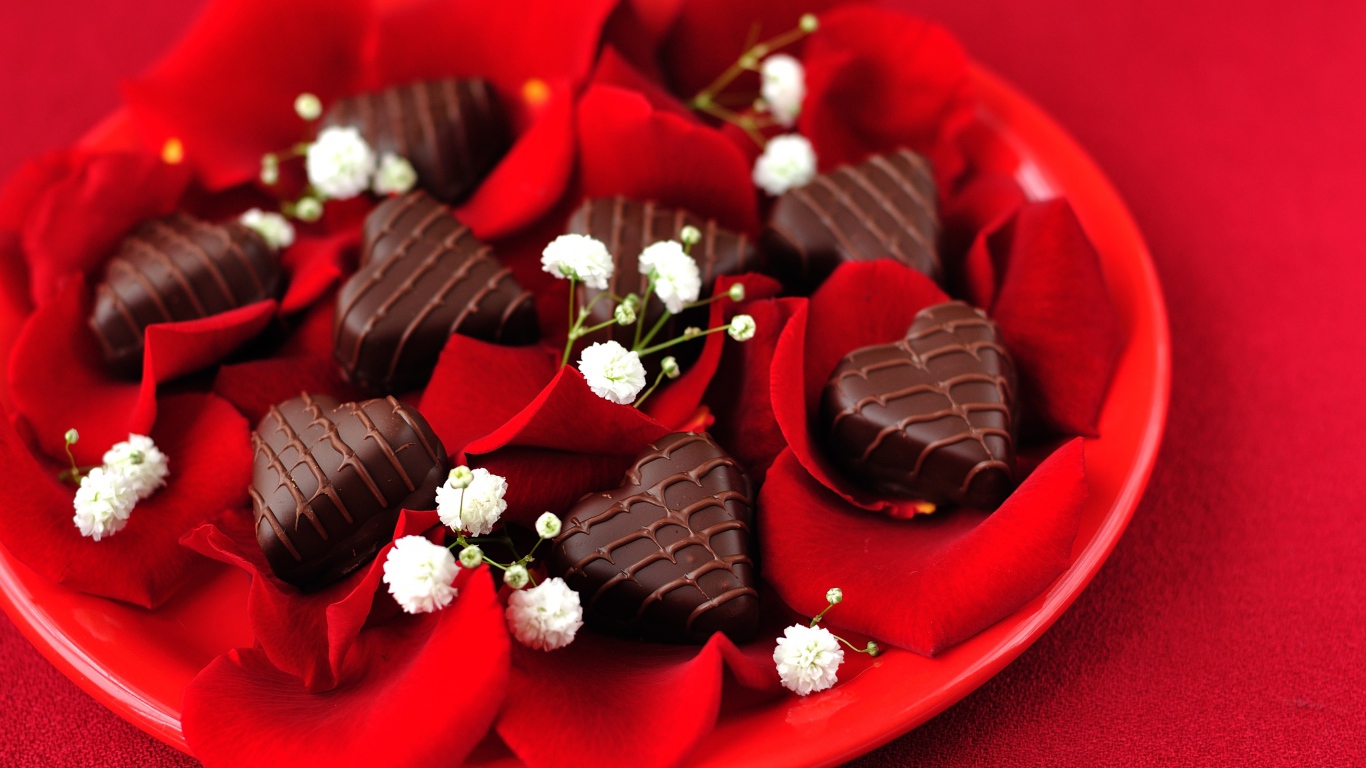 Шоколадные конфеты в форме сердца на тарелке с лепестками розы