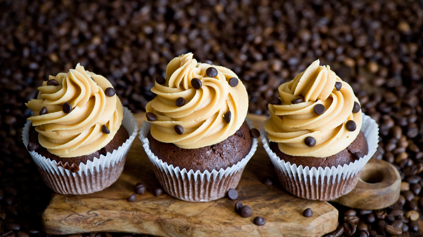 Кексы с кремом и зернами кофе на столе 