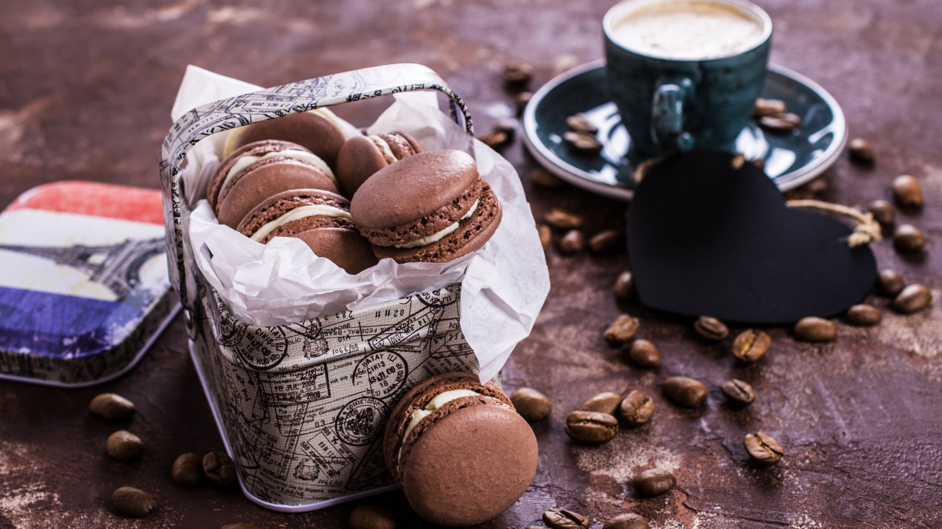 Десерт макарон на столе с кофейными зернами и чашкой кофе