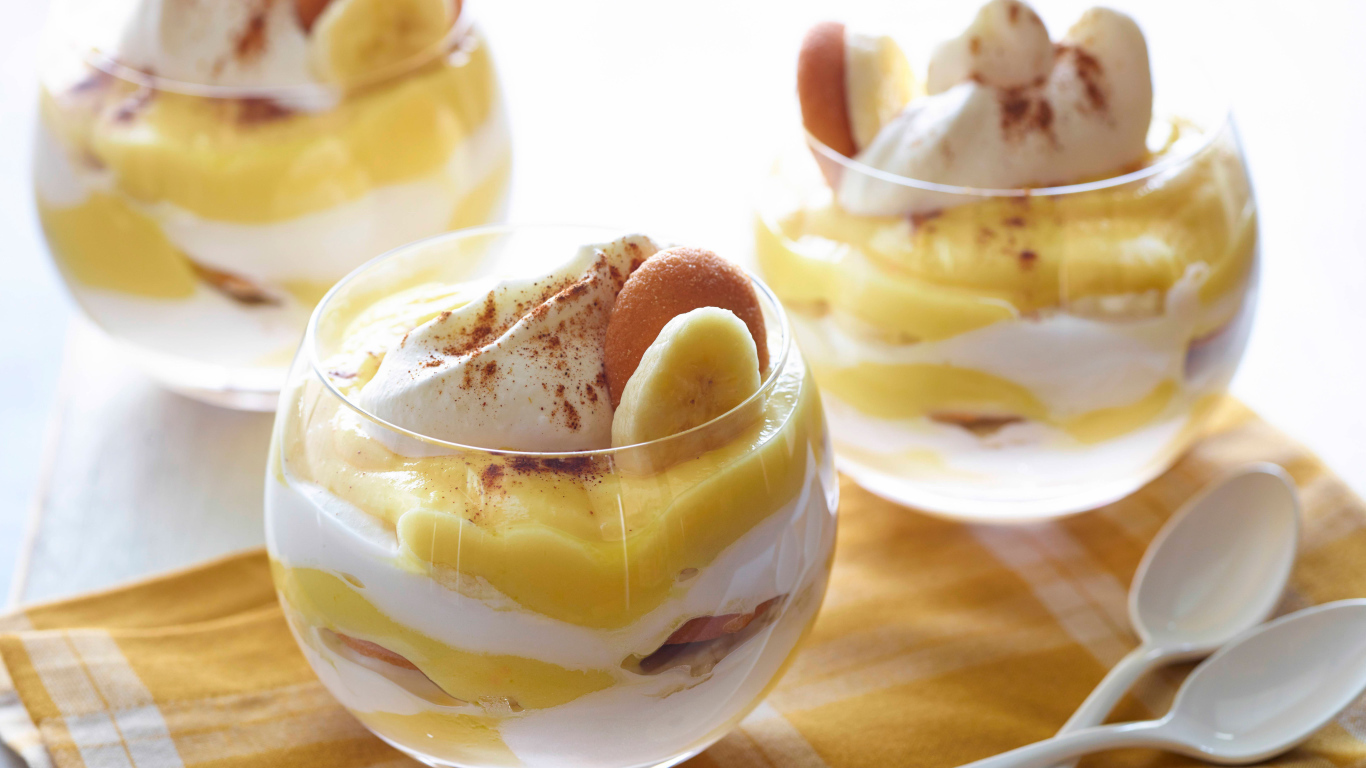 Десерт с бананами и печеньем в стаканах на столе 