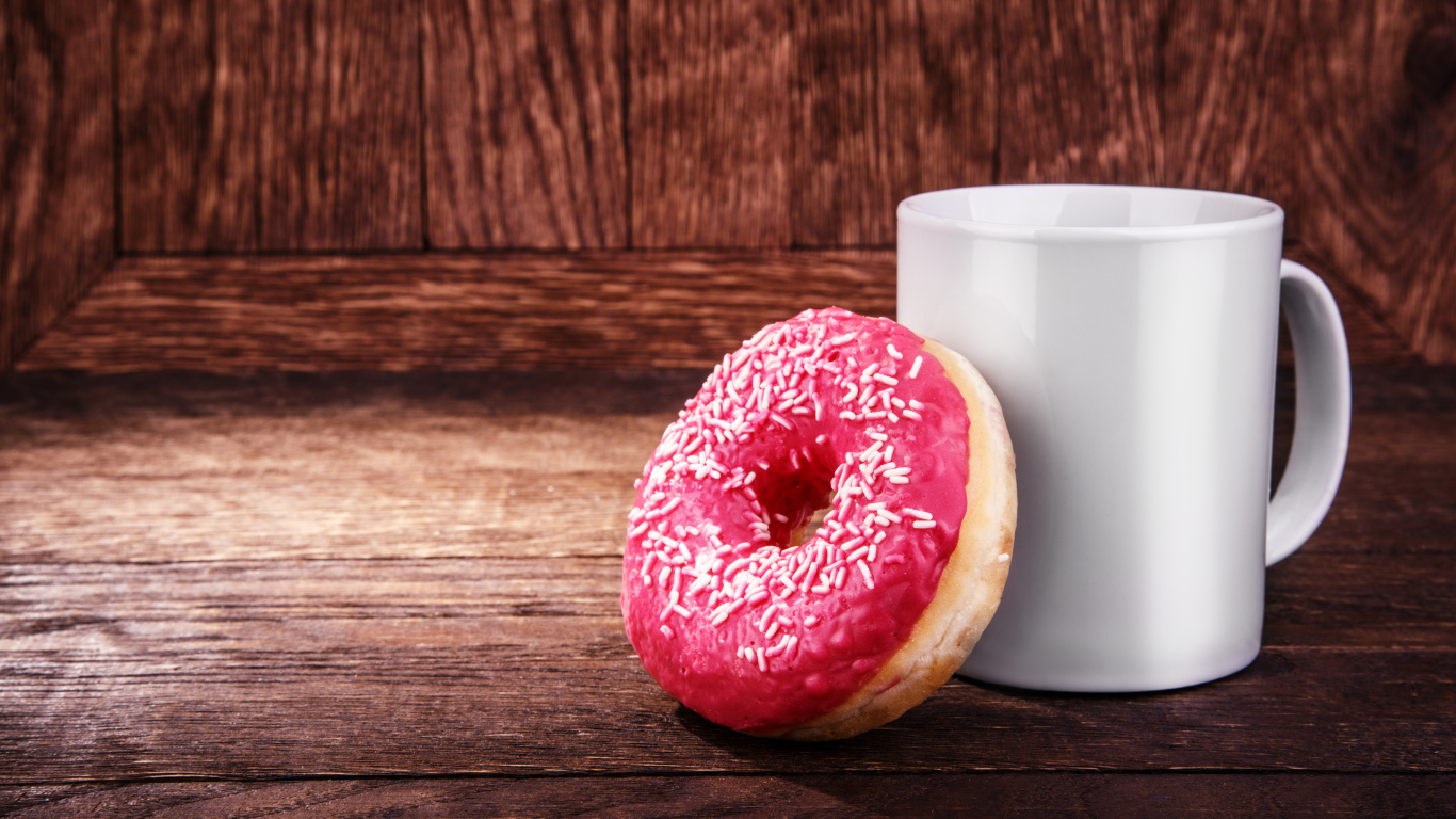 Пончик с белой кружкой на деревянном столе