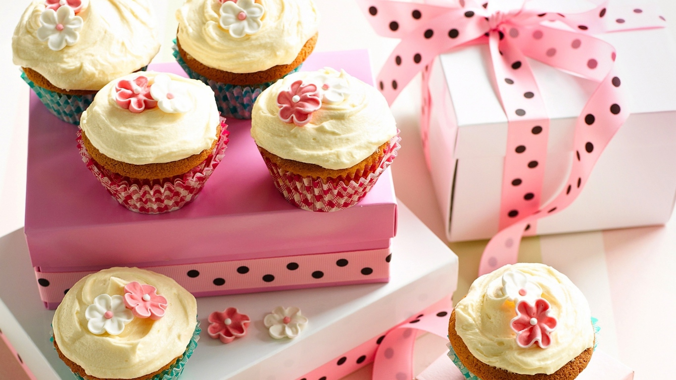 Праздничные кексы с кремом и подарочной коробкой на столе