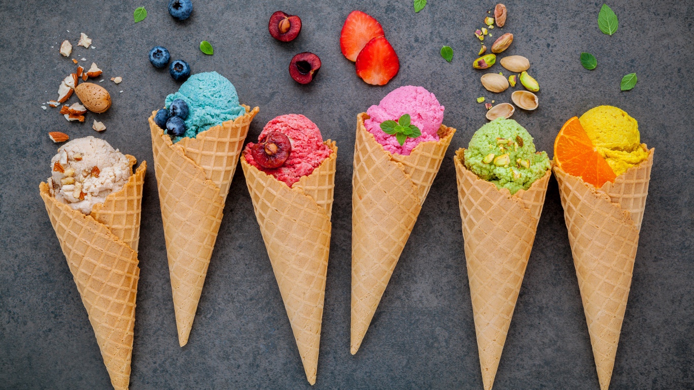 Шарики фруктового мороженого в вафельных рожках на сером фоне