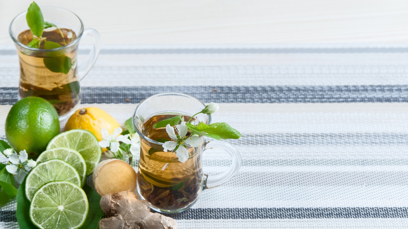 Стеклянные чашки с чаем на столе с имбирем и лаймом