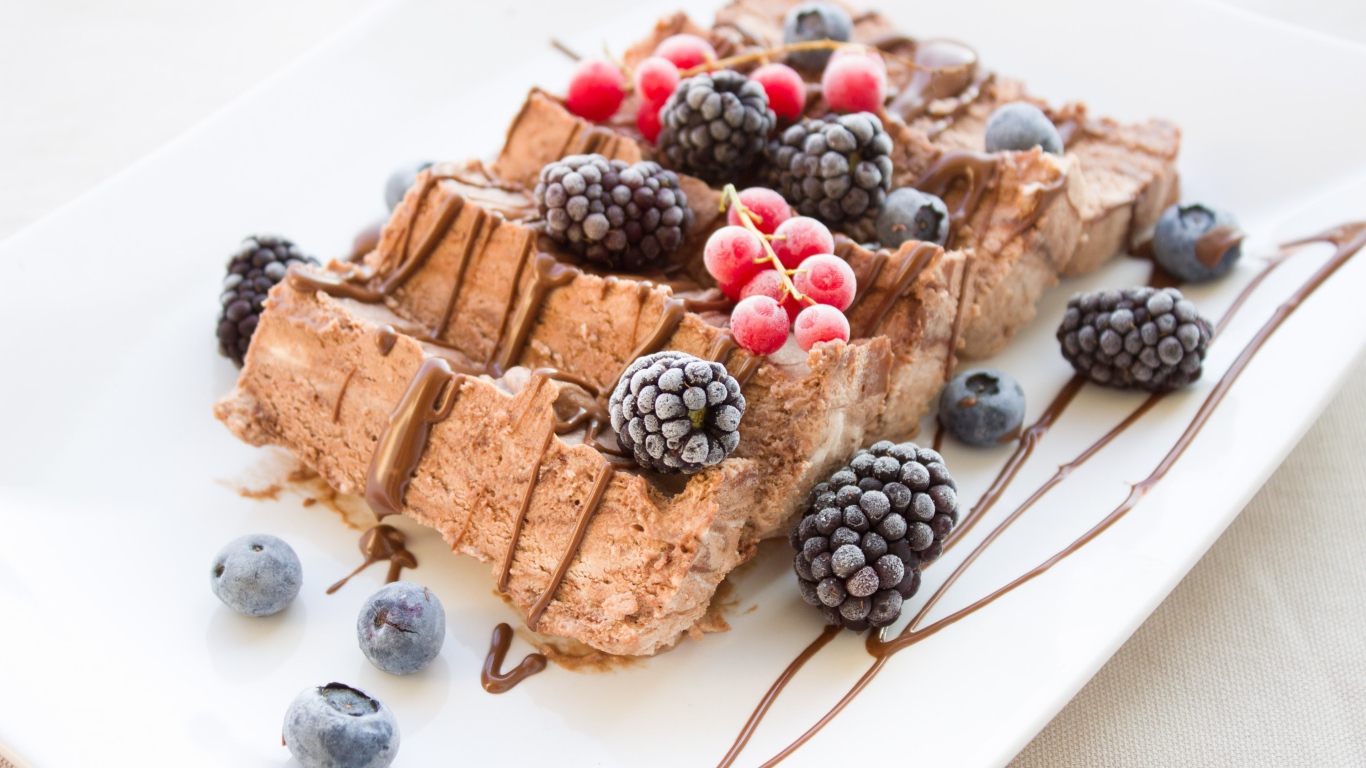 Мороженое с ягодами ежевики и красной смородины на белой тарелке 