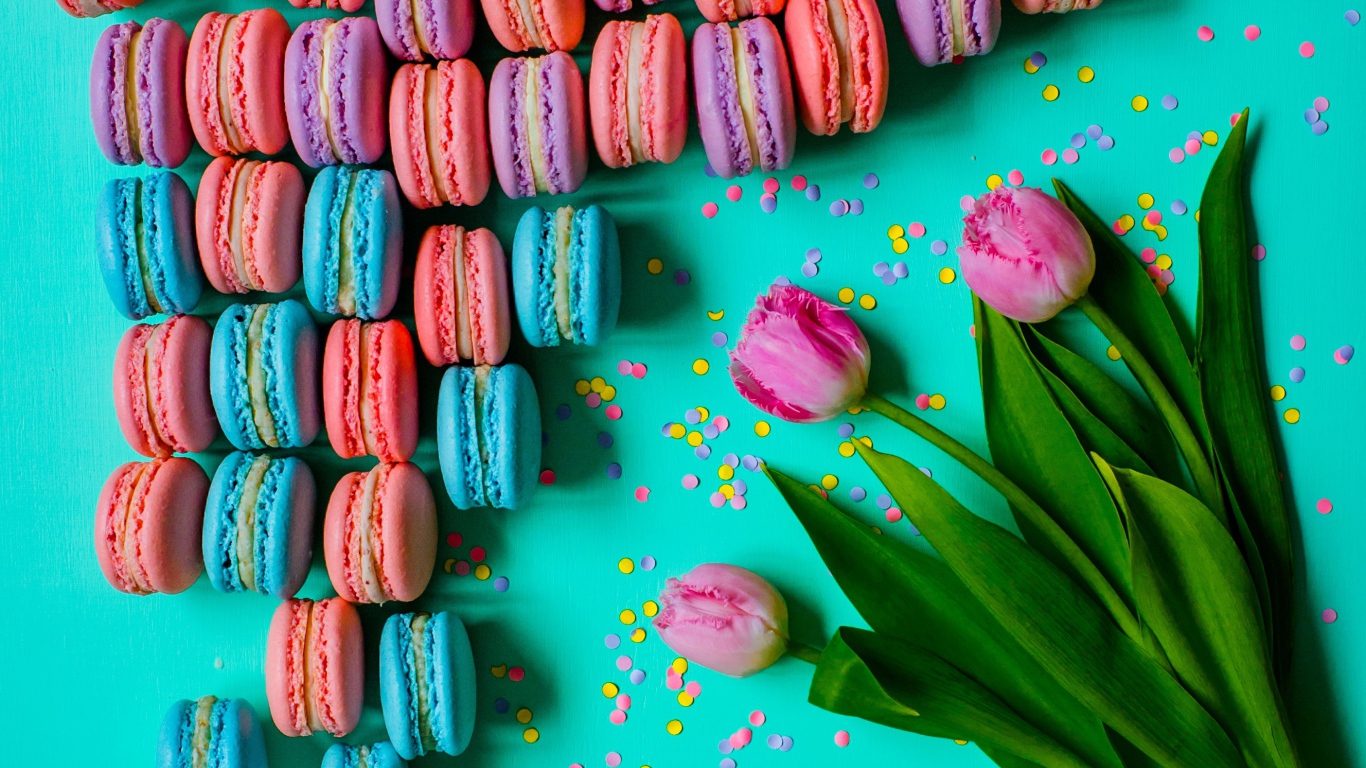 Разноцветные десерты макарун на столе с тюльпанами