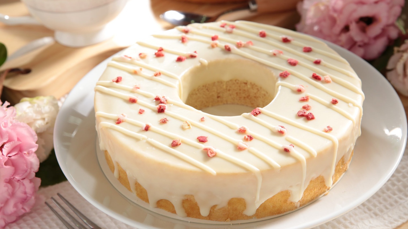 Круглый кекс с глазурью на белом блюде 