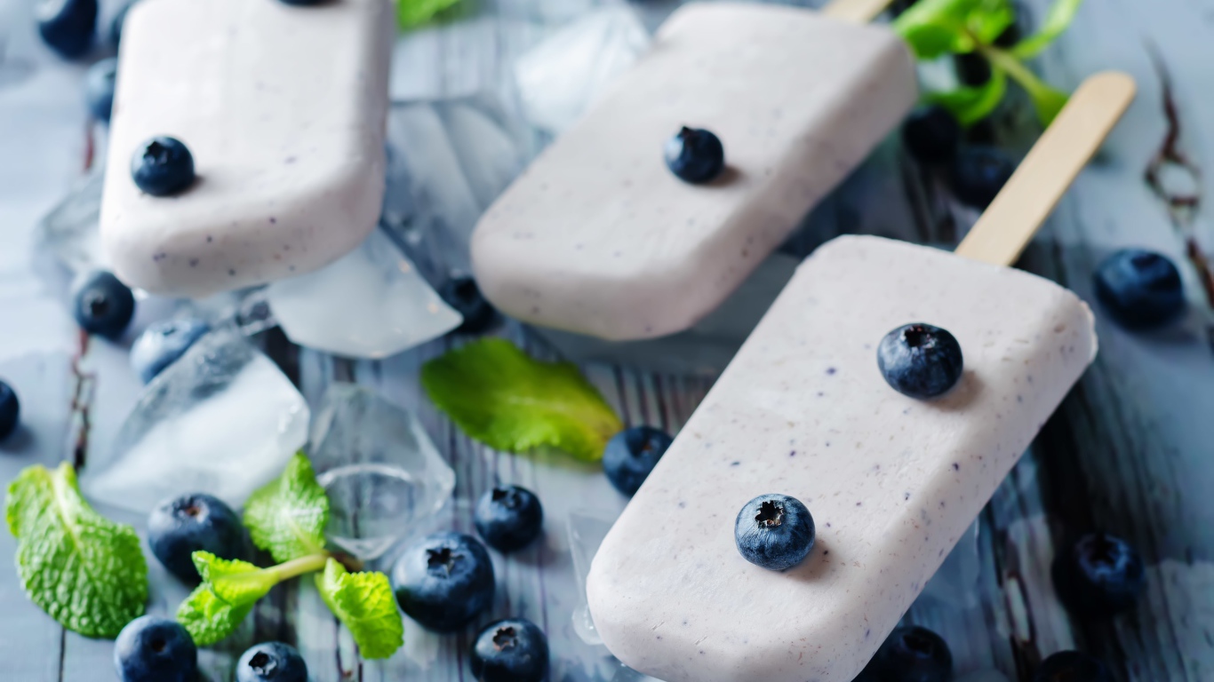 Вкусное мороженое с ягодами черники на столе с кусочками льда