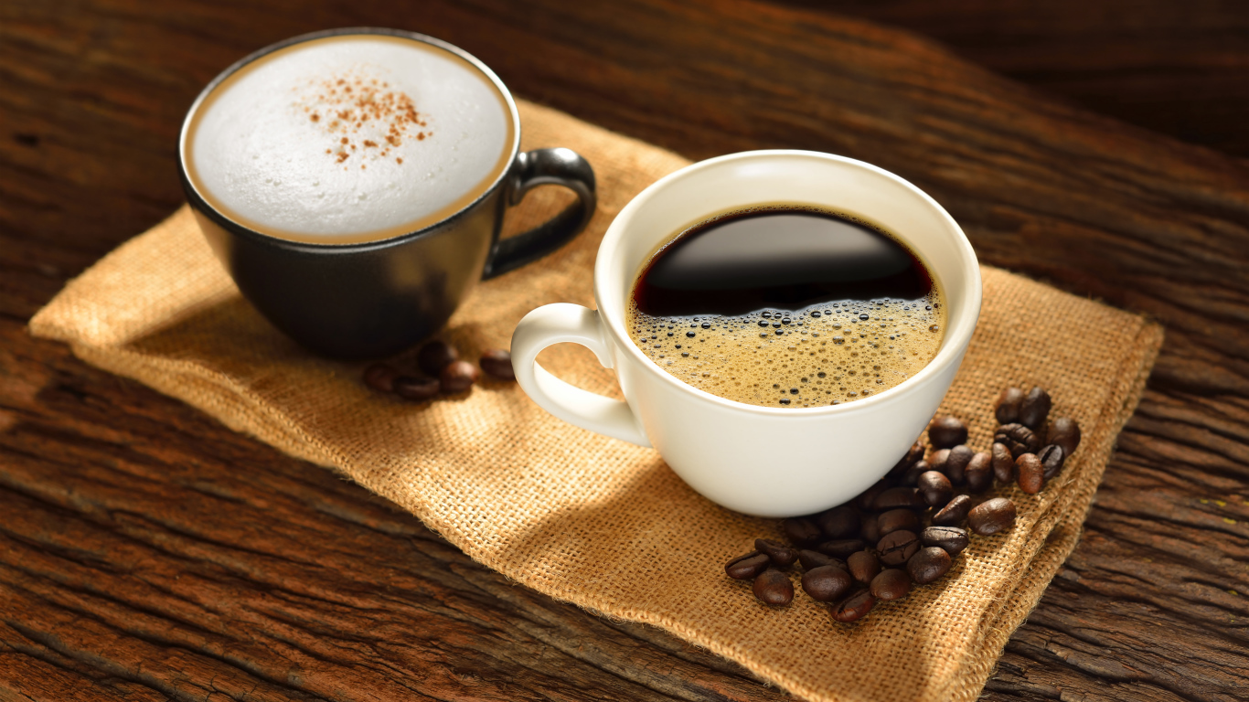 Чашка кофе и чашка капучино на столе с кофейными зернами
