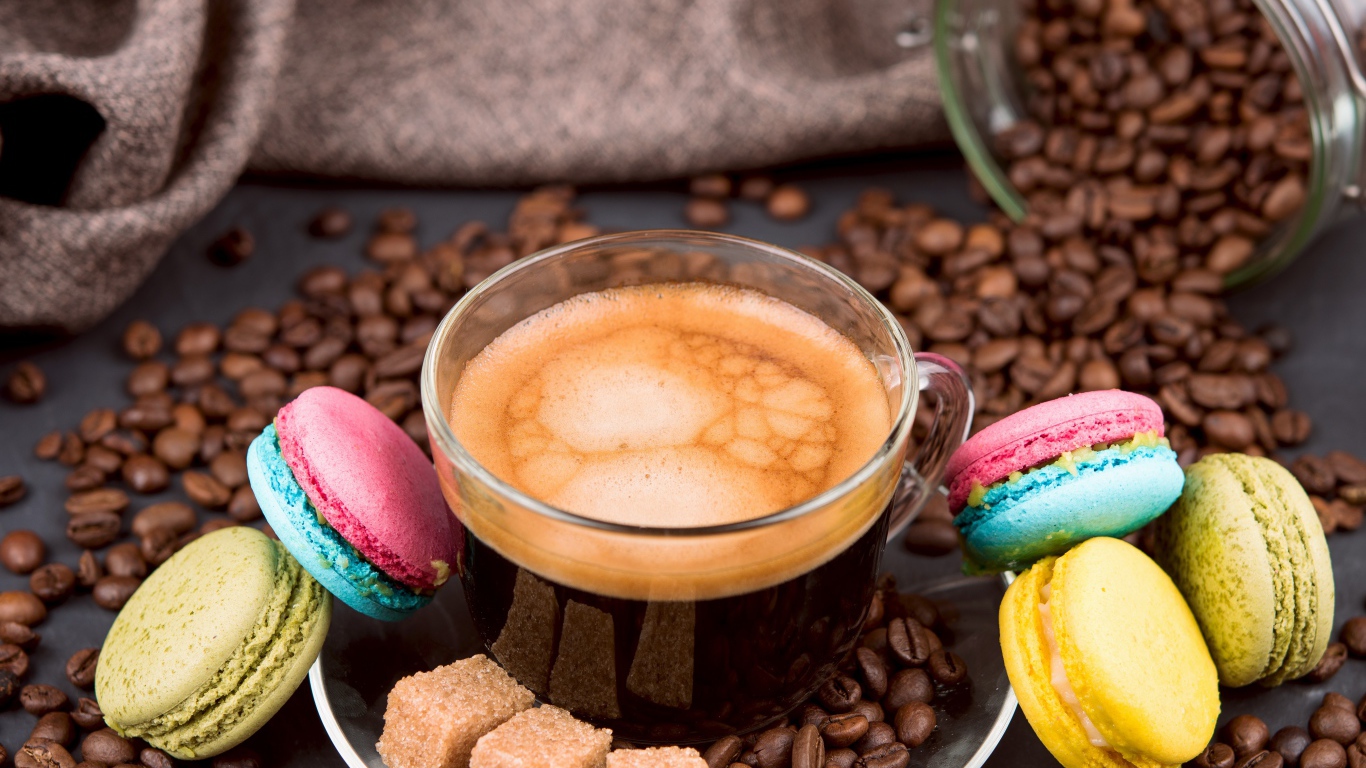 Чашка кофе с кофейными зернами, кубиками сахара и десертом макарон