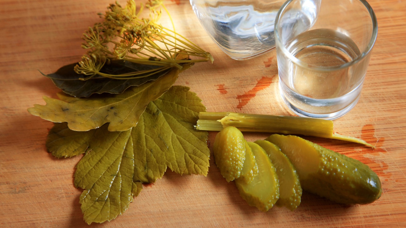 Рюмка водки на столе с соленым огурцом