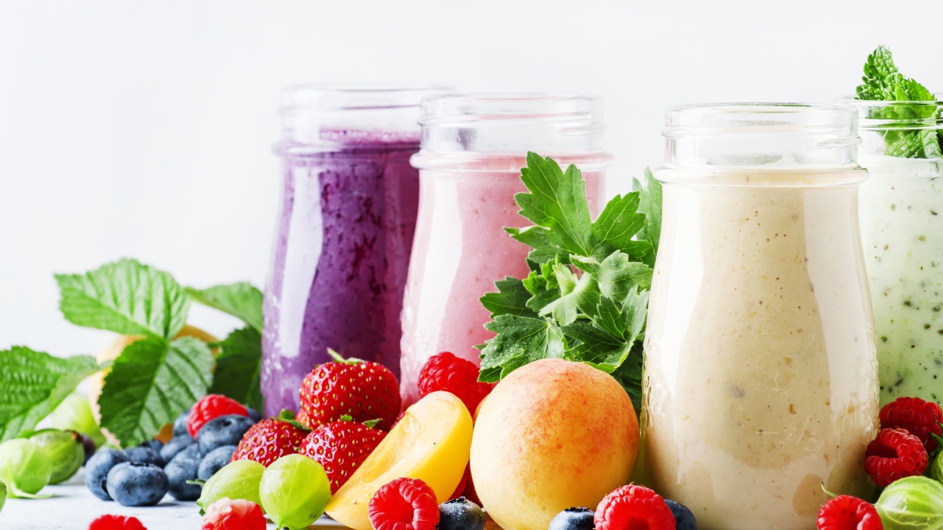 Ягодные смузи в бутылочках на столе с ягодами