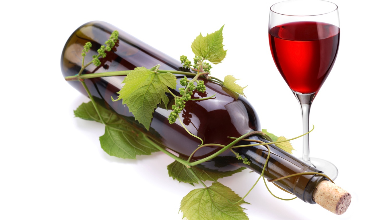 Бутылка вина в виноградной лозе с бокалом на белом фоне