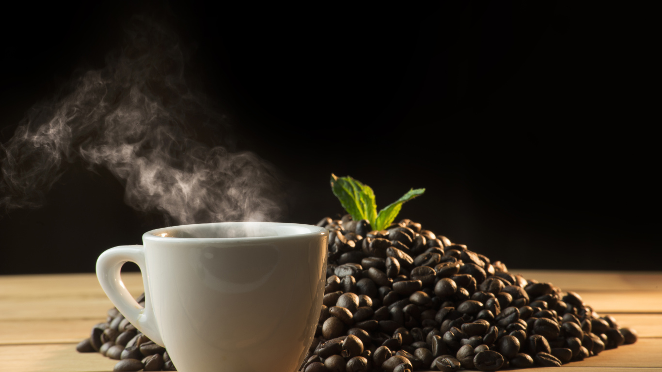 Кофейные зерна на столе с чашкой горячего кофе 