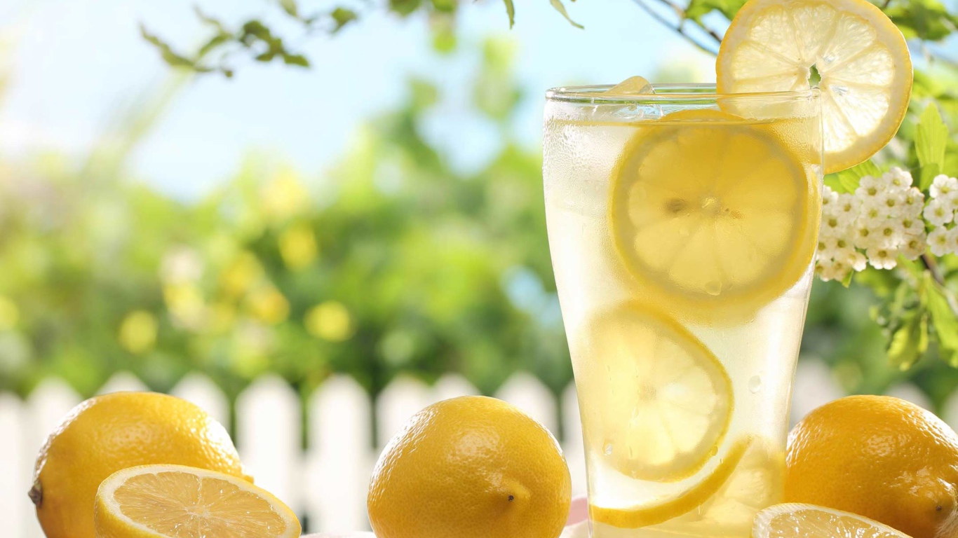 Холодный лимонад в стакане с кусочками лимона