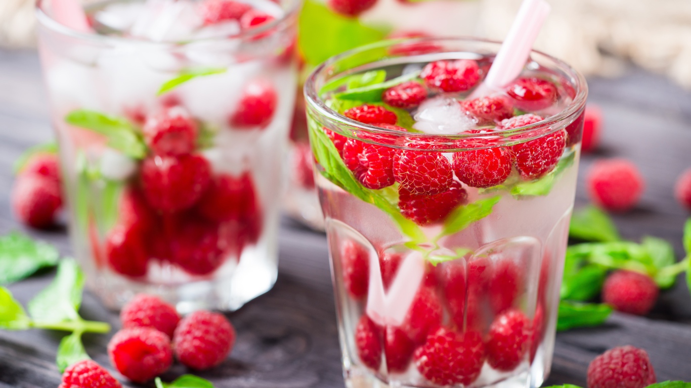 Напиток в стакане с малиной и кубиками льда