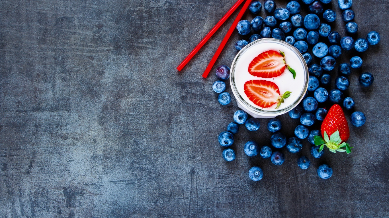 Молочный коктейль с клубникой и черникой на столе 