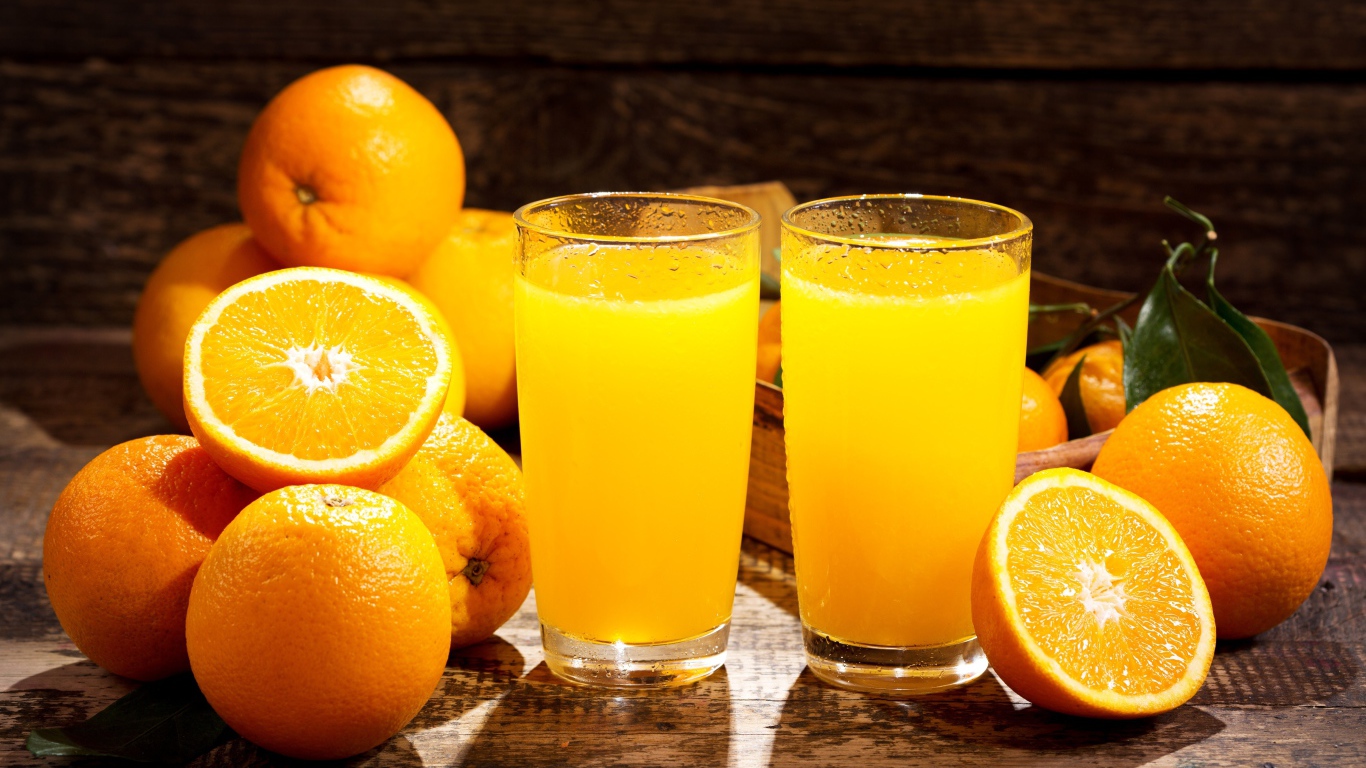 Два стакана свежего апельсинового сока на столе с фруктами