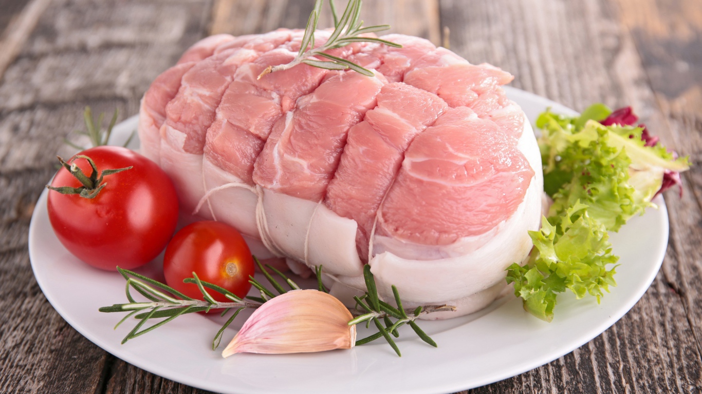 Кусок свежего мяса со свежими помидорами, чесноком и листьями салата