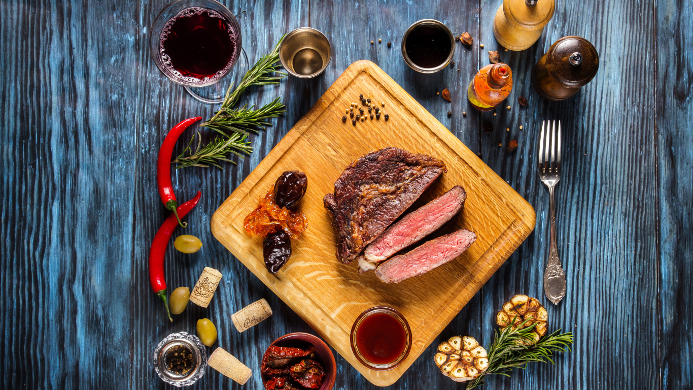 Кусок мяса на столе со специями и стаканом вина