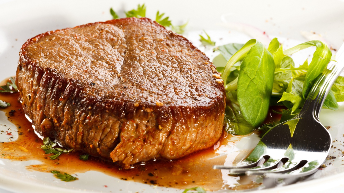 Отбивная с зеленым салатом на тарелке с вилкой