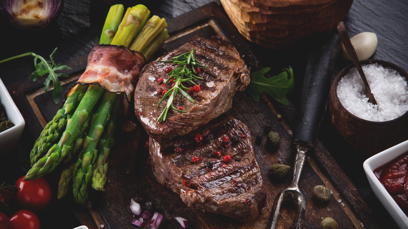 Жареное мясо с зеленой спаржей на столе 