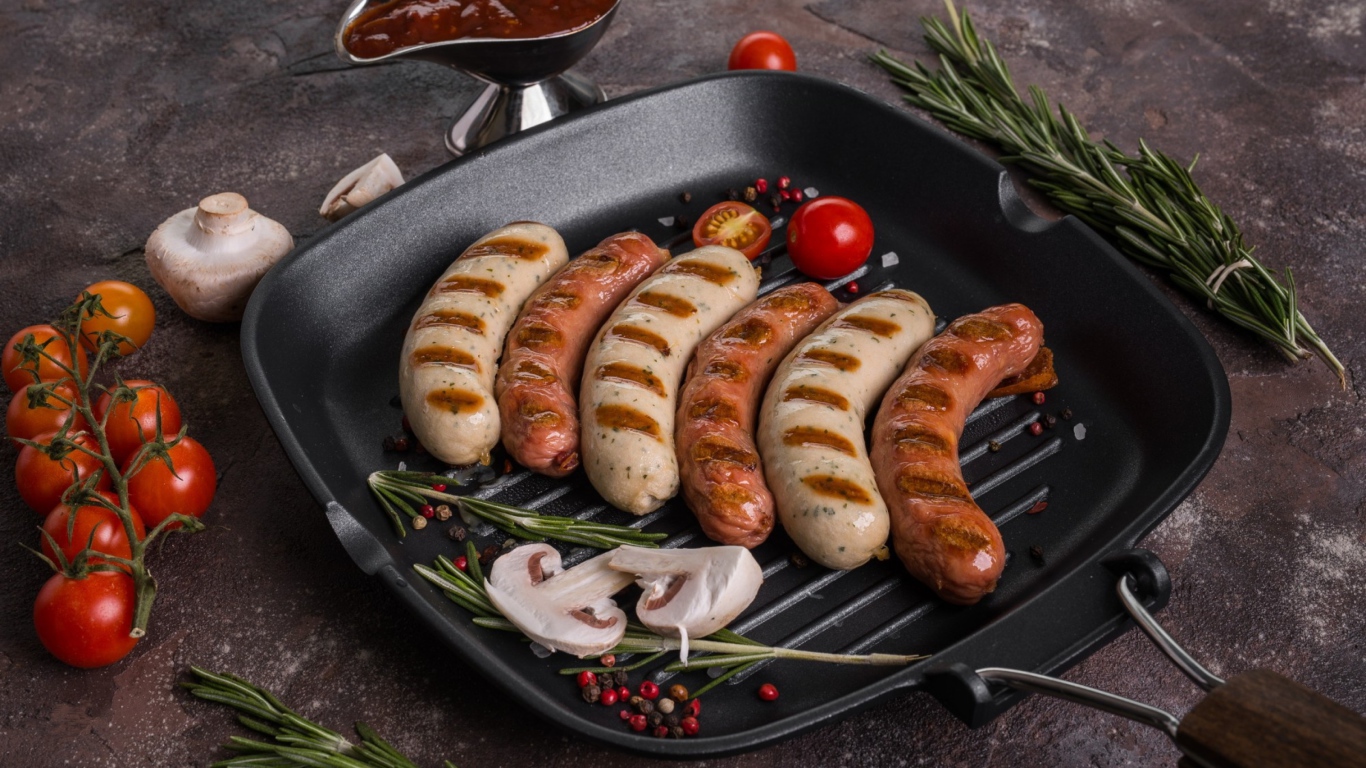 Колбаски гриль на столе с овощами 