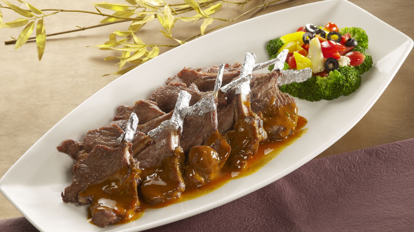 Мясо на белой тарелке с соусом и овощами 