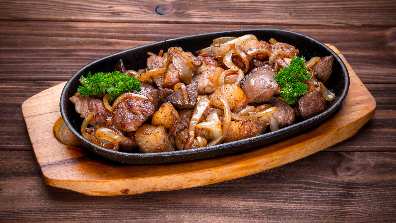Кусочки шашлыка с луком и петрушкой в сковороде