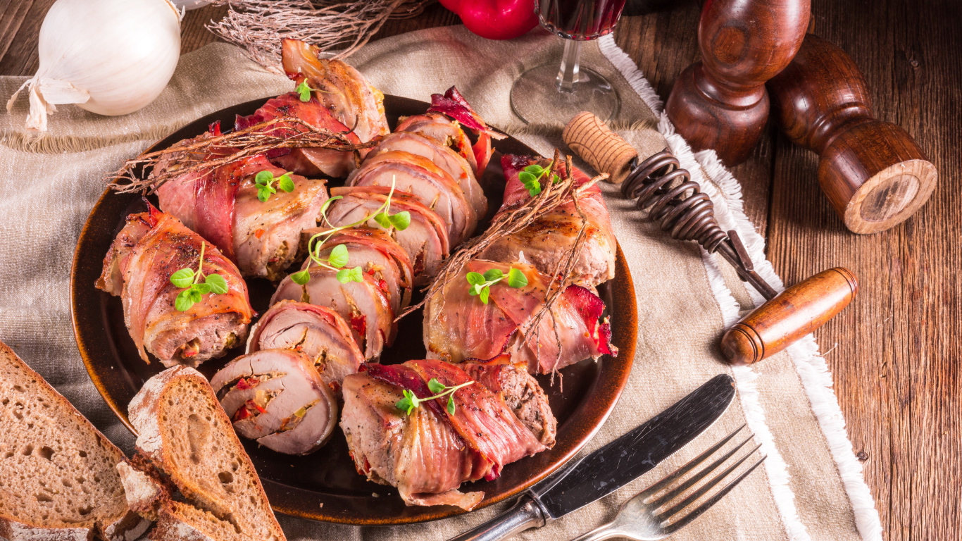 Нарезанные мясные рулеты на столе с хлебом