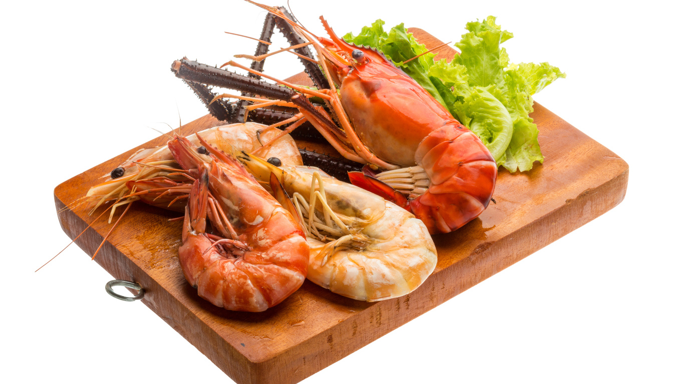 Вареные креветки с листьями салата на разделочной доске