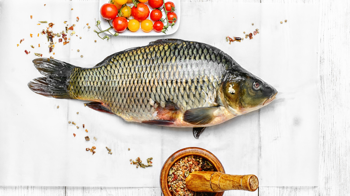 Свежий карась на столе со специями и помидорами