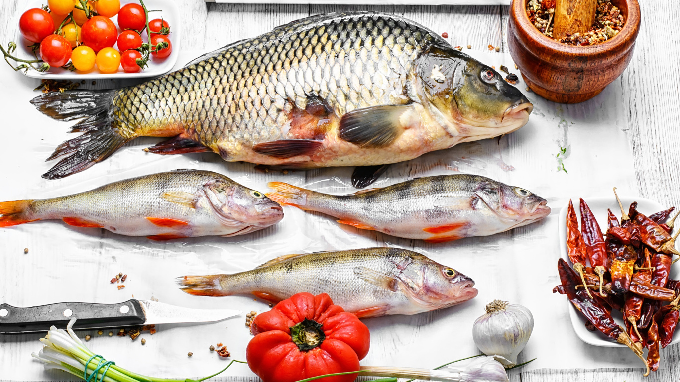 Свежая рыба на столе с помидорами, зеленым луком и  специями