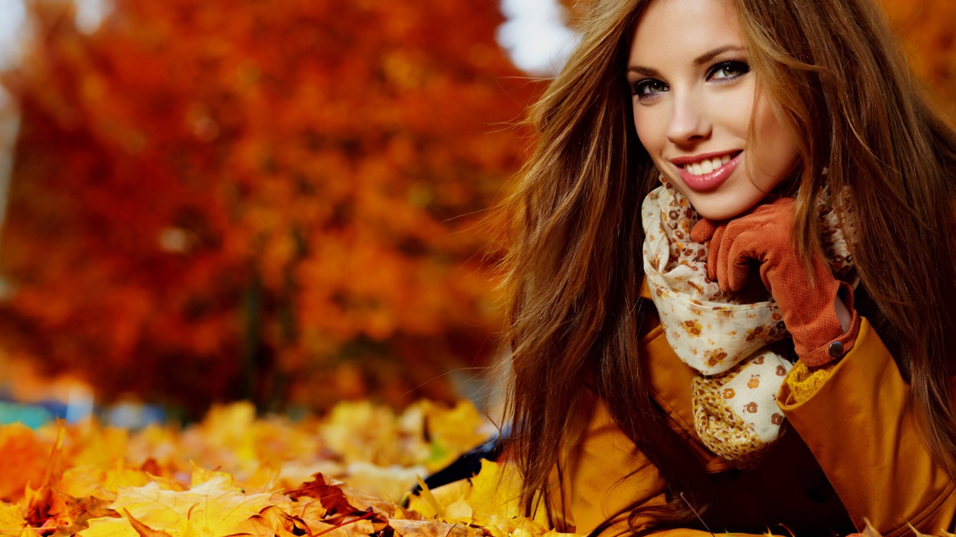 Красивая девушка лежит на опавших осенних листьях