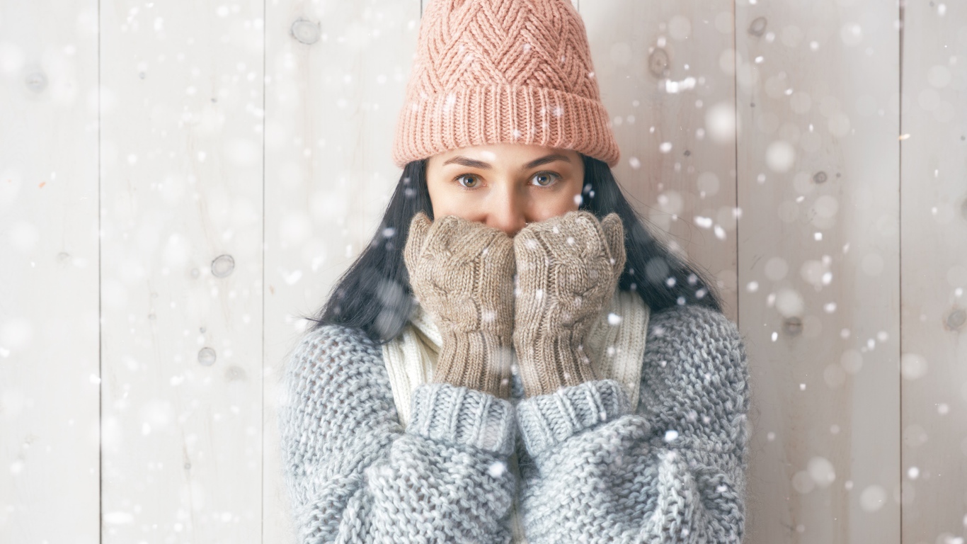 Молодая девушка с теплом свитере с шапкой на голове и перчатках