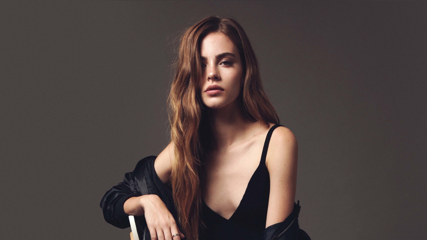 Красивая брюнетка в черном платье сидит на стуле