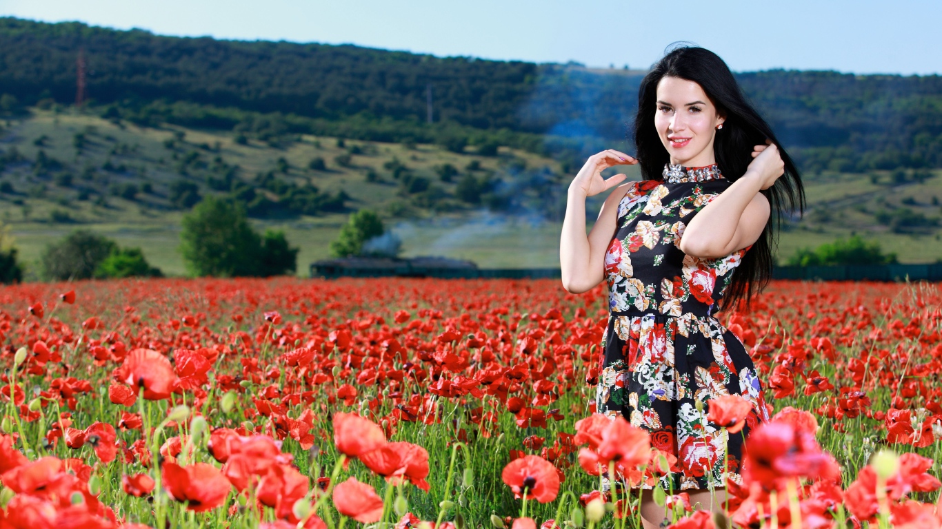 Красивая брюнетка стоит на поле с красными маками