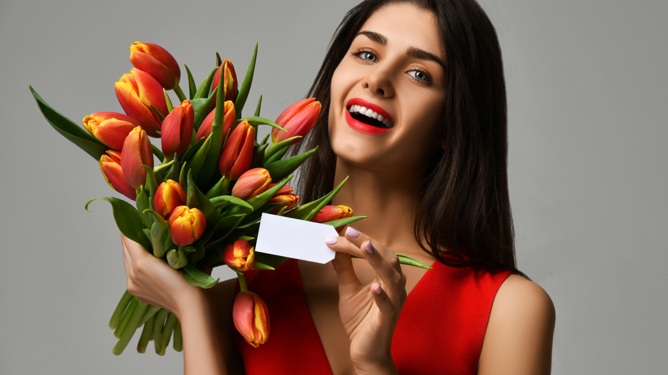 Красивая брюнетка с букетом тюльпанов на сером фоне