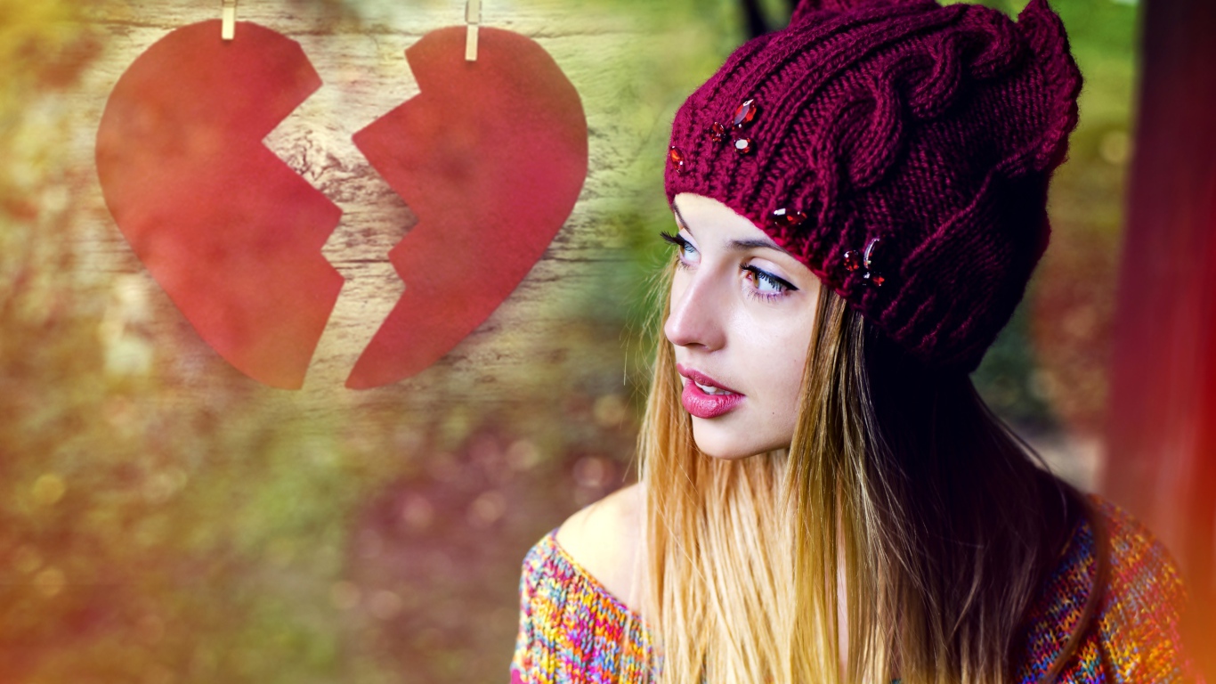 Красивая девушка в вязаной шапке на фоне разбитого сердца